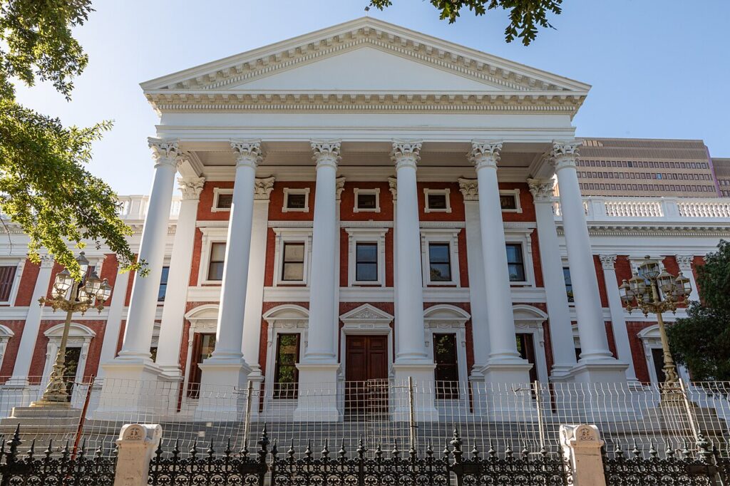 The grand neoclassical parliament building with tall fluted columns, a triangular pediment and wide stone steps under a clear sky, conveying