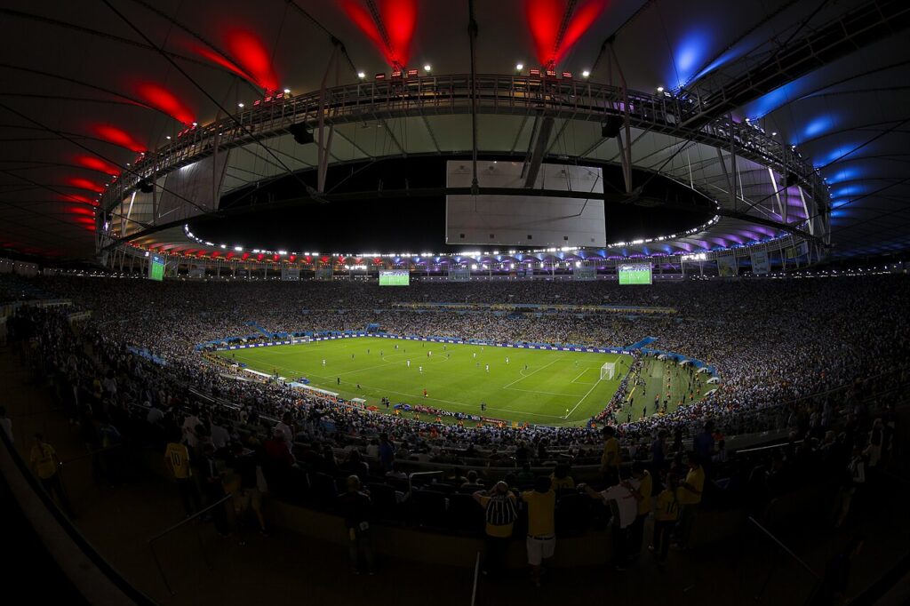 A wide-angle photograph of a major international football stadium under floodlights during a knockout-stage match, with two opposing teams c