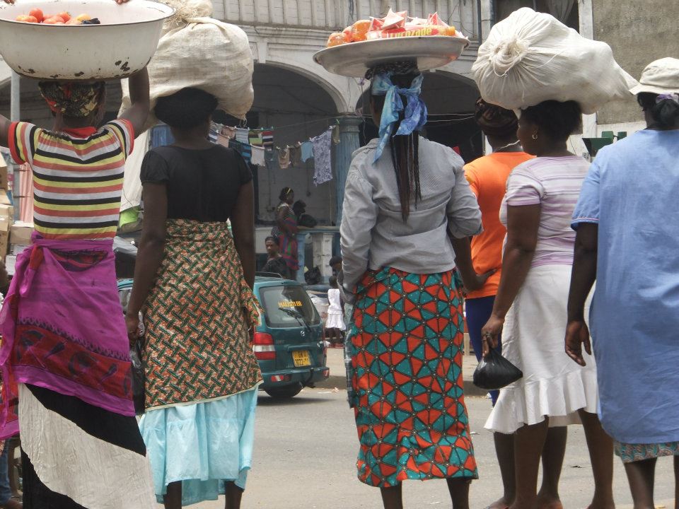 A busy urban street in a West African capital with cars, taxis and pedestrians moving through midday traffic.