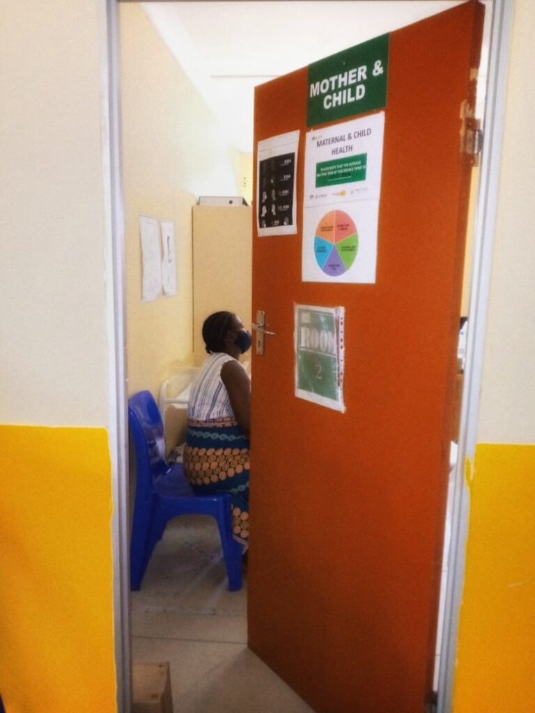 A middle-aged woman consulting with a female healthcare professional in a brightly lit clinic examination room, with a stethoscope visible o