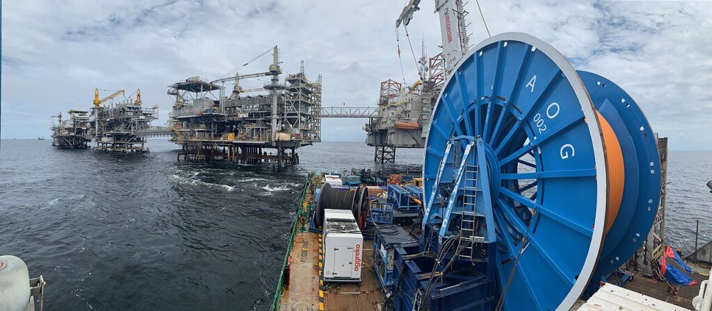 An offshore oil platform standing in deep open sea off the coast of Angola, with industrial derricks and drilling towers visible against a c