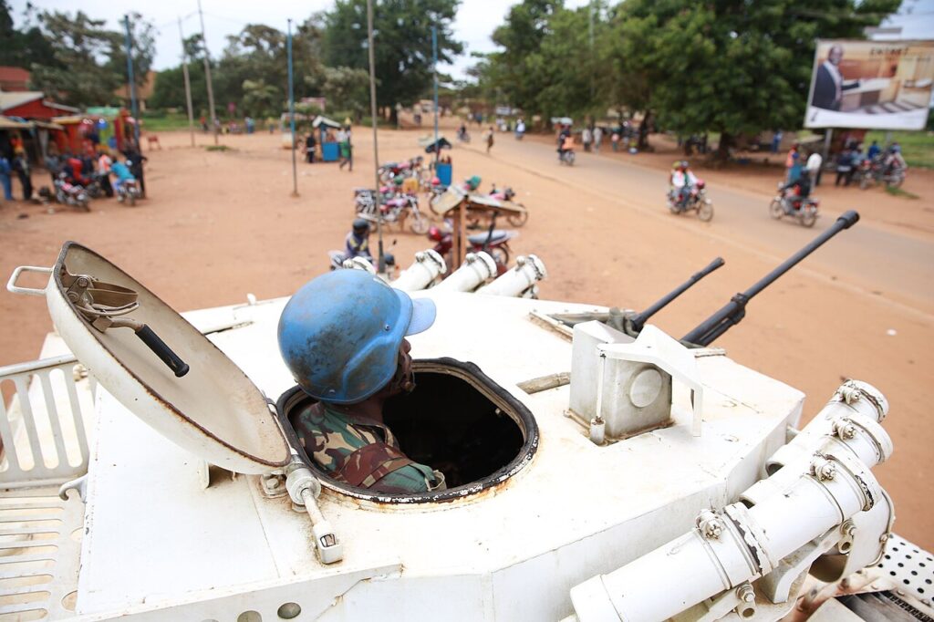 A health worker in protective gear stands at the entrance of a rural medical treatment centre in DR Congo.