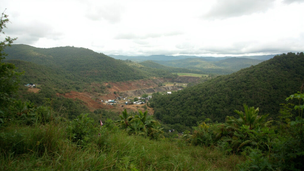 Rolling green highlands of eastern DRC with an artisanal mining site carved into reddish-brown earth.