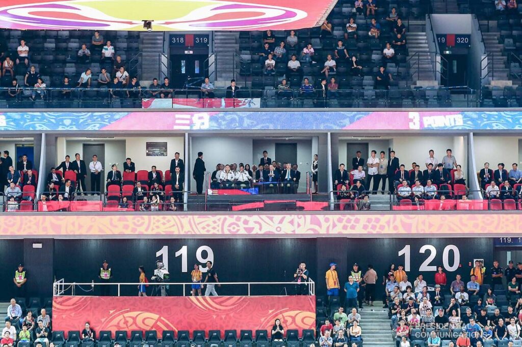 An indoor basketball arena during an international women's exhibition match between two national teams.
