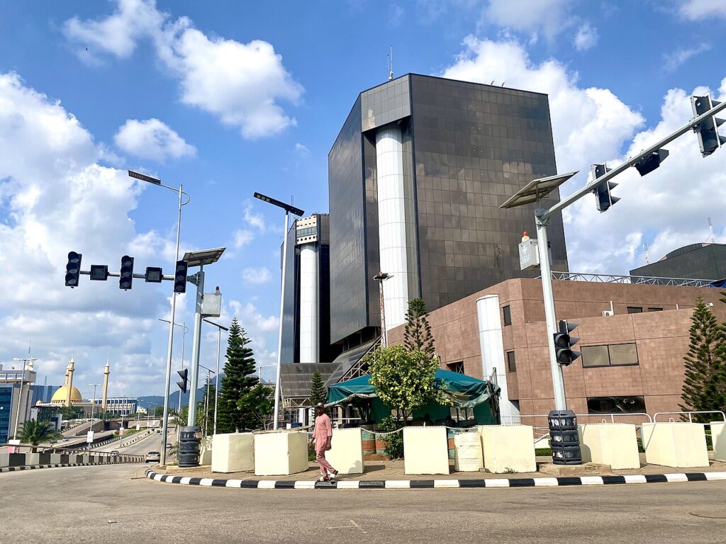 An exterior view of a modern glass-and-concrete corporate tower in a West African capital at midday.