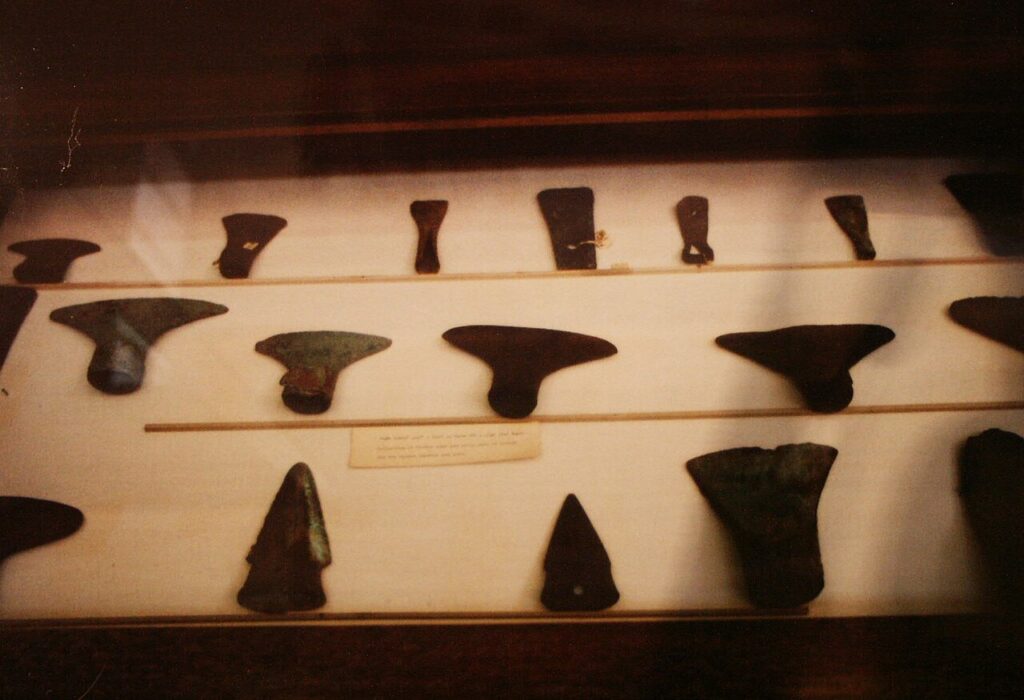 An archaeologist carefully holds a small ancient artifact during a repatriation ceremony with officials in the background.