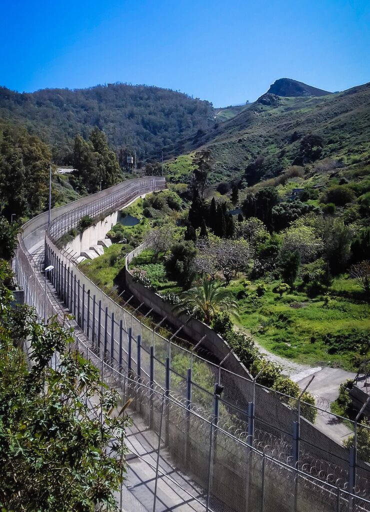 A view of the border fence between the Spanish enclave of Ceuta and neighboring Morocco, with the Mediterranean Sea visible in the backgroun