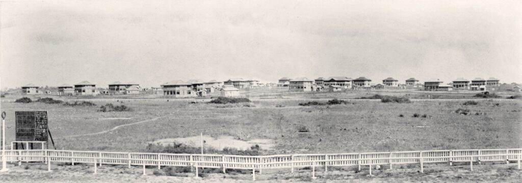 A densely populated West African urban neighbourhood with mid-rise concrete residential buildings of varying states of completion, photograp