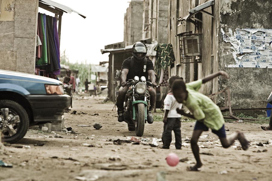A crowd of onlookers in an urban Nigerian street recording an incident with smartphones, illustrating how punishment has become shareable di