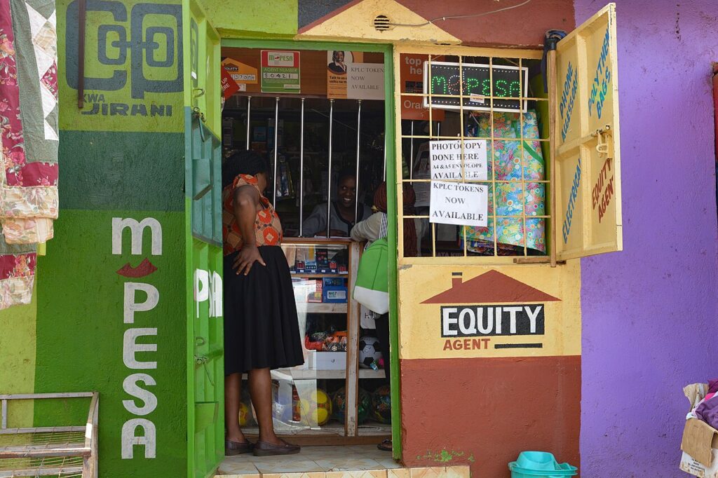 A person uses a smartphone for a mobile lending or mobile money transaction on a busy street in an East African city.