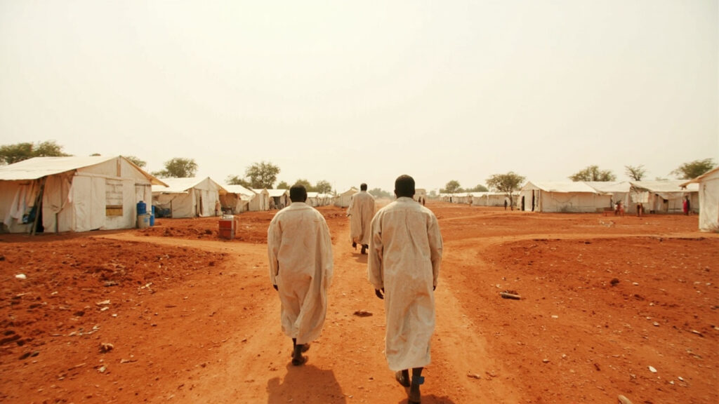 A refugee settlement in arid northern Kenya with rows of white tents under harsh midday sun.