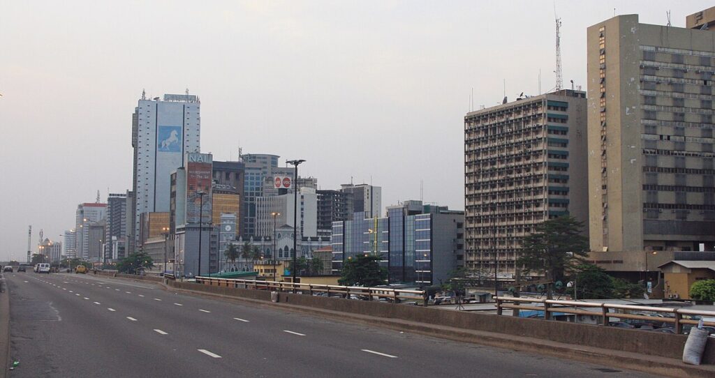 An aerial or skyline view of central Lagos showing the commercial district's high-rise buildings and waterways under bright tropical light.