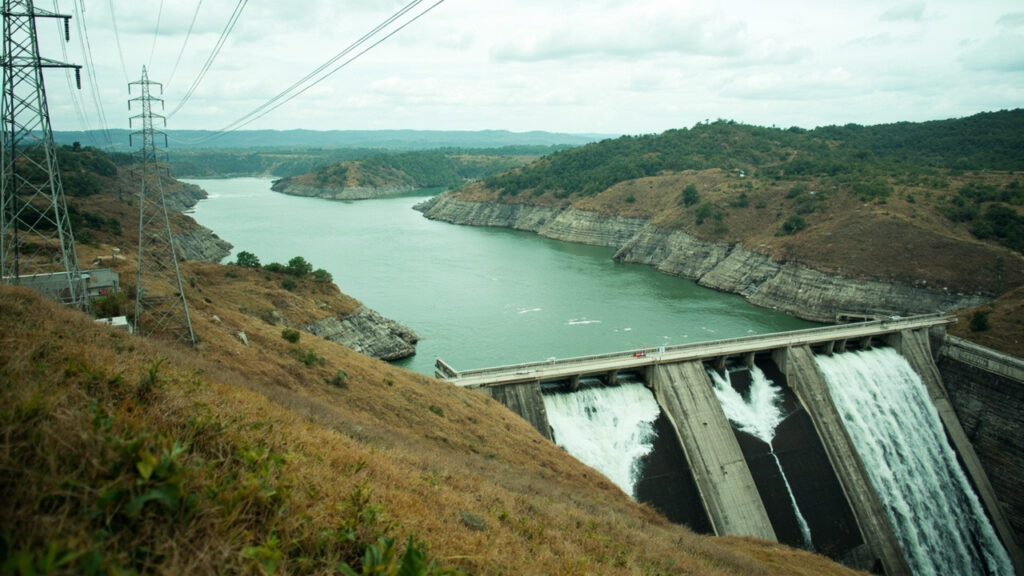 A hydroelectric dam and high-voltage transmission towers along a river valley.