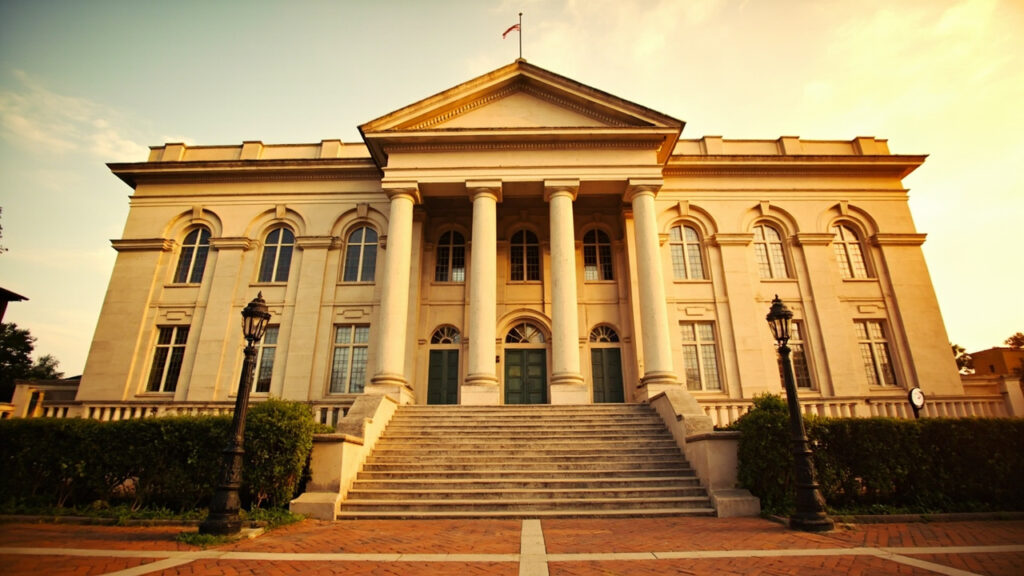 Colonial-era government building facade with arched windows and columned portico in late afternoon light.