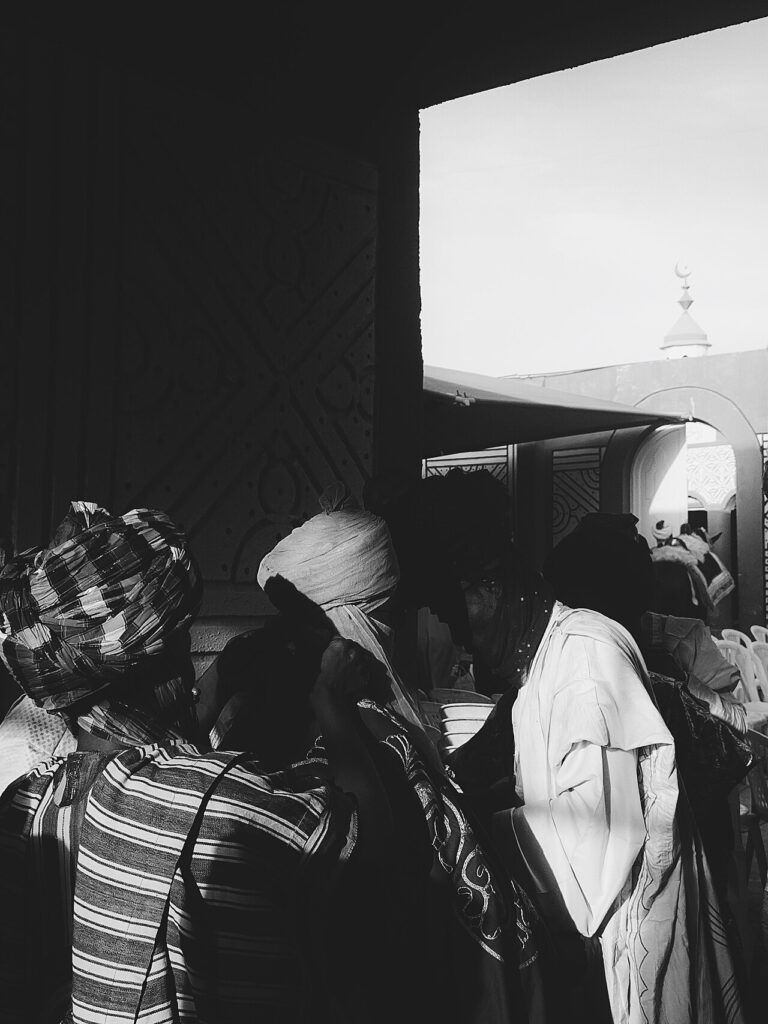 A large indoor gathering of couples dressed in colorful traditional attire during a mass wedding ceremony in northern Nigeria.