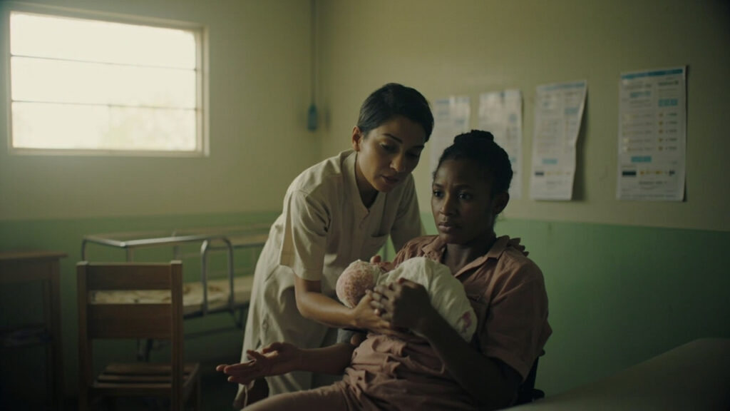 A mother cradles her newborn at a community health clinic while a nurse provides guidance on infant feeding.