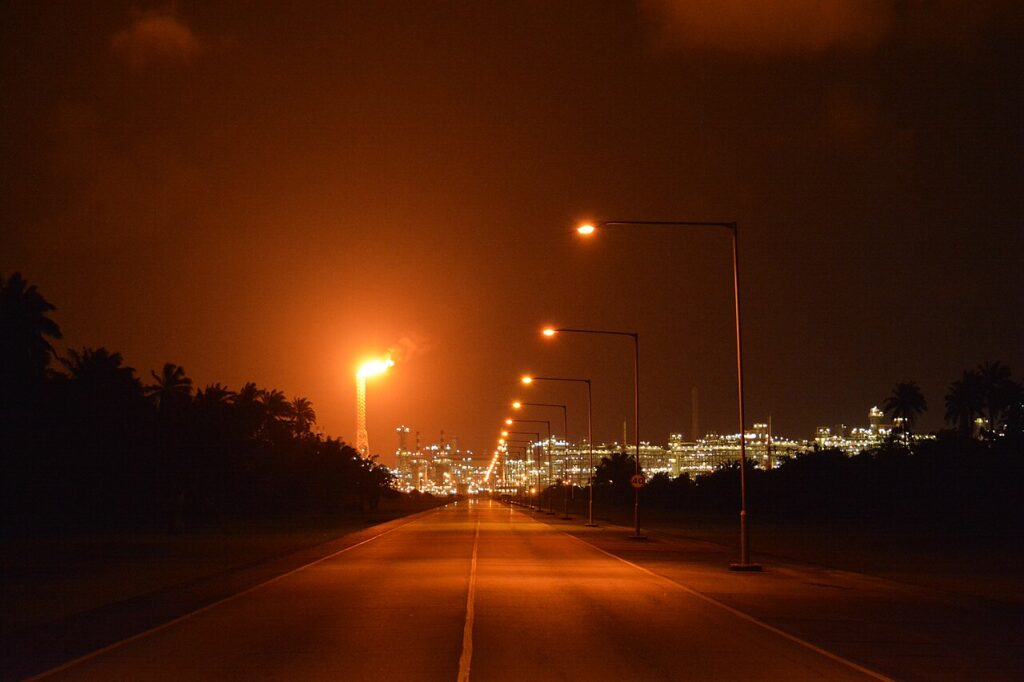 An offshore liquefied natural gas facility at dusk with illuminated processing structures against a dark coastal horizon.