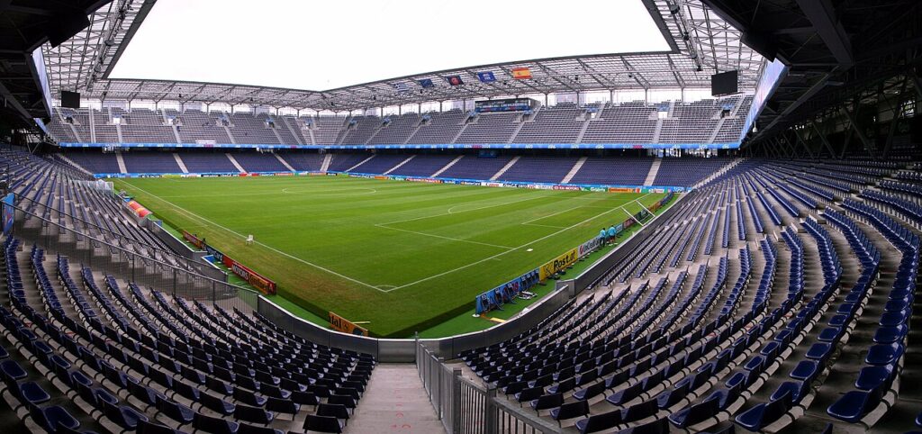 A football match being officiated at a modern European stadium under floodlights.