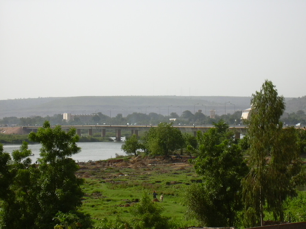 A wide exterior view of a West African government building in Bamako, the capital of Mali, with visitors arriving at the entrance.