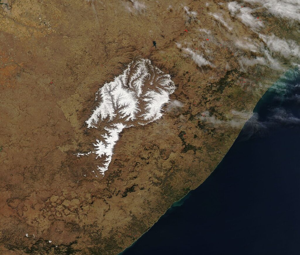 Snow-covered mountain peaks in South Africa with overcast skies and windswept white landscapes.