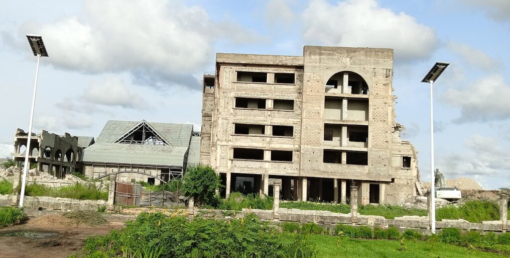 An exterior view of a formal government building in Porto-Novo, Benin, featuring symmetrical columns, ornate stonework, and a wide entrance
