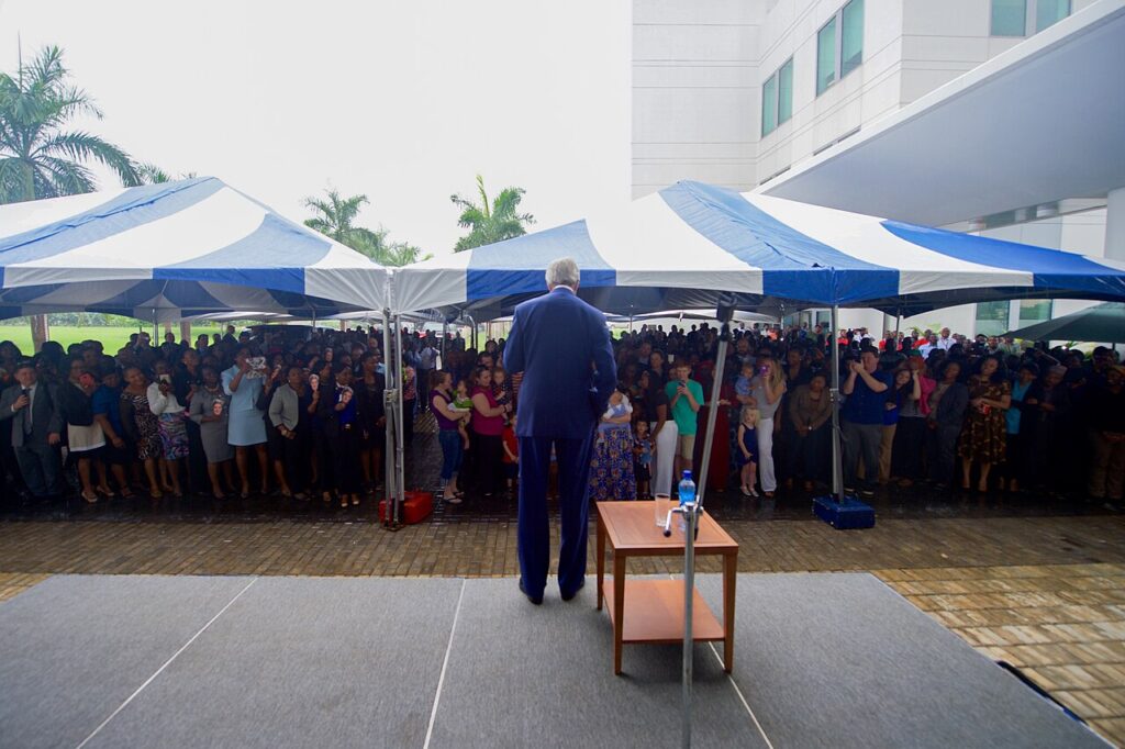 A formal award ceremony at a diplomatic venue with officials and a recipient holding a recognition plaque.