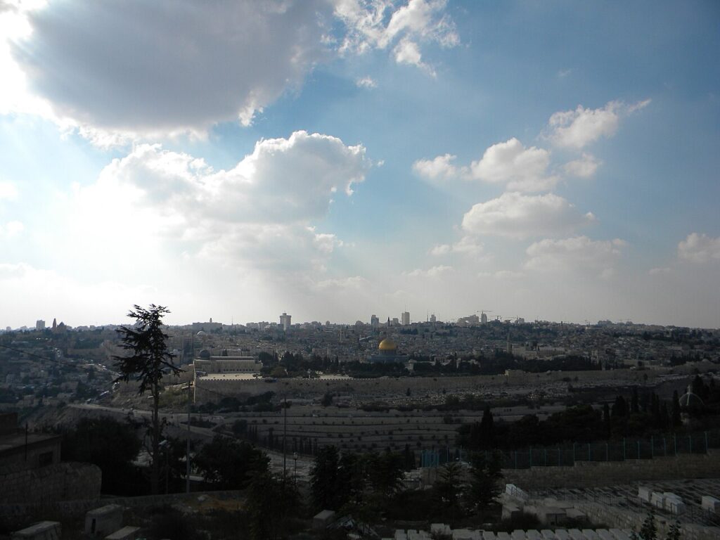A panoramic view of the Old City of Jerusalem showing stone walls, domed rooftops and narrow streets under clear daylight.