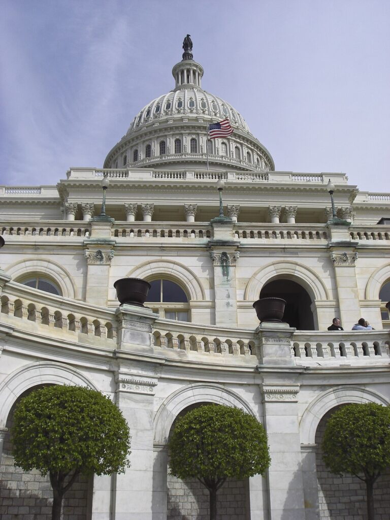 Exterior view of the US Capitol dome and neoclassical facade seen from across the lawn on a clear day.