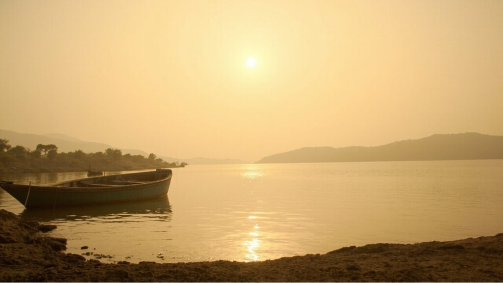 A wide view of Lake Kariba at golden hour, with calm water stretching toward distant hills and small boats near the shoreline.